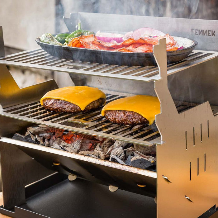 Fennek Grill im Einsatz mit zweitem Grillrost, unten ein Grillrost zum Grillen von Cheeseburger und oben ein Grillrost zum Warmhalten.