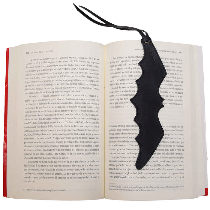 Leather Bat Bookmark from Hide & Drink inserted in an opened book, highlighting its practical use for avid readers. This Bat Bookmark is a stylish gift for bookworm friends, combining function and flair. Each piece is hand cut and sewn, offering artisan craftsmanship from Guatemala and Mexico.