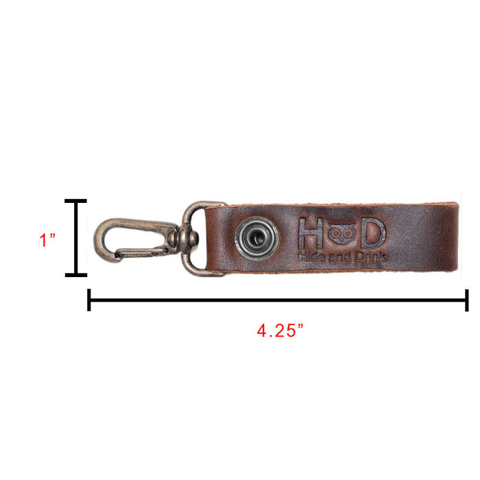 Belt Key Holder by Hide & Drink displaying its dimensions and specifications, designed for functionality and style. Dimensions Length: 4.25 in. Height: 1 in. Width: 0.50 in. Made of Full Grain Leather, it will assume a unique patina over time; conditioning is advisable with mineral oil or beeswax.
