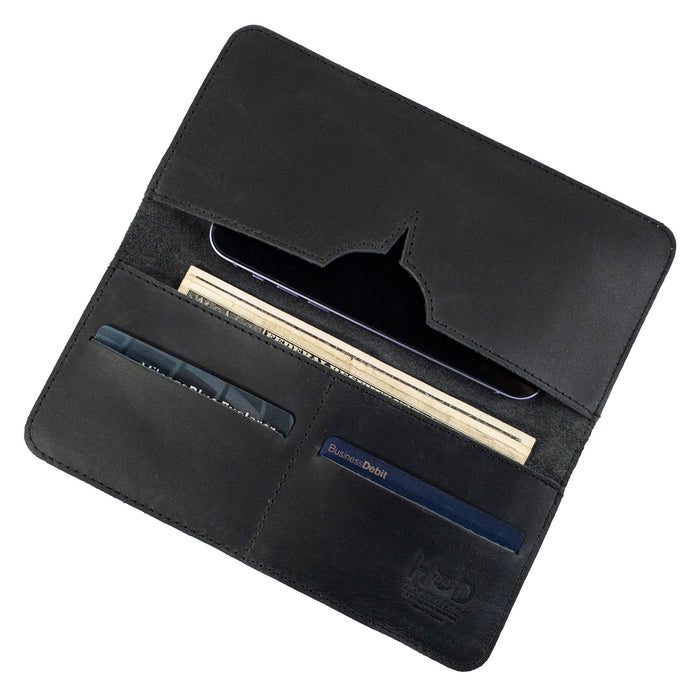 Open black bifold wallet for cellphone by Hide & Drink, displaying card slots and cash compartment. This Bifold Wallet for Cellphone pairs premium Full Grain Leather with ideal organization features. Handcrafted with care in small batches by artisans in La Antigua Guatemala & Oaxaca Mexico.