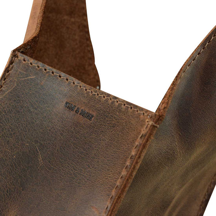 Close-up of the Bottle Wine Carrier by Hide & Drink, emphasizing the craftsmanship and full grain leather texture. This squared bottle wine carrier with handle is a perfect Bordeaux bottle holder and rustic case, ideal for picnic accessories. Handmade in La Antigua Guatemala and Oaxaca Mexico, it features small batch production and fire branded artisan details.