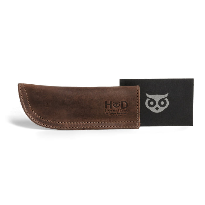 Hide & Drink Cast Iron Panhandle Cover featured with its packaging. This artisan hot handle protector exemplifies the quality of full grain leather and artisan craftsmanship. Hand cut and sewn in La Antigua Guatemala & Oaxaca Mexico, it provides a secure grip for your skillet while being a stylish kitchen addition.