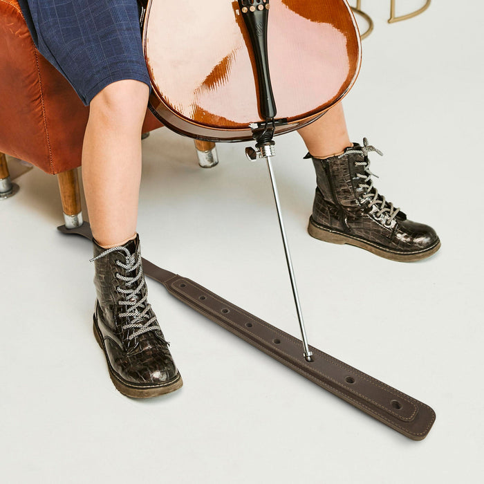 A Cello Endpin Strap Stopper in action, shown with a cello and a musician‚Äôs stylish boots. This Classic Non-Slip Stopper by tocame ensures stability and protects floors while practicing. Made from durable full grain leather, this artisan accessory exemplifies small batch production and handcrafted excellence.
