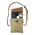 Hide & Drink Crossbody Bag featuring an open design with items inside including a phone, money, and a pen. This Crossbody Bag with Adjustable Shoulder Strap is a Unisex Messenger Bag crafted from Full Grain Leather & Waxed Canvas, showcasing small batch production, hand cut, hand sewn, fire branded craftsmanship by artisans in La Antigua Guatemala & Oaxaca Mexico.