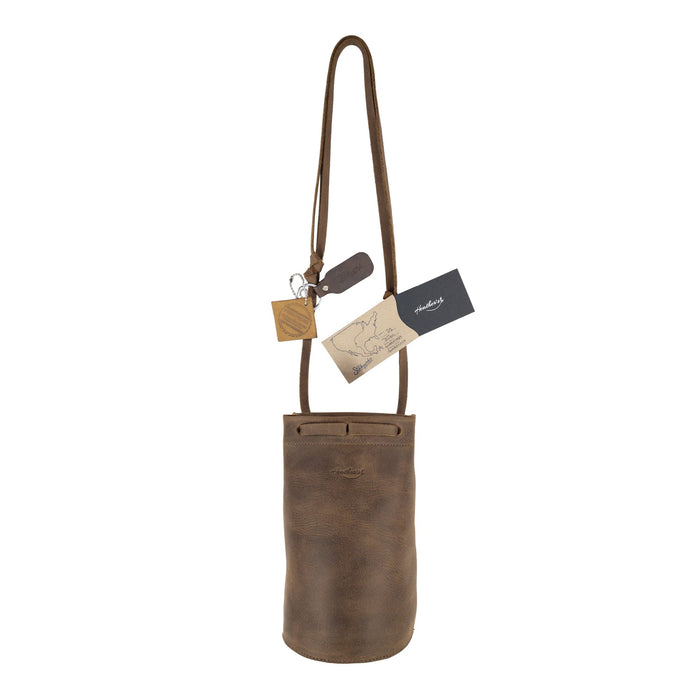 Heather's Cylinder Shoulder Phone Bag with tags and branding displayed, highlighting its artisan quality. This fashionable cylinder-shaped purse with adjustable shoulder strap is crafted from full grain leather, showcasing the artisan approach from StockyardX and reinforcing the values of small batch production and meticulous hand cut, hand sewn techniques. Handmade in La Antigua Guatemala & Oaxaca Mexico.
