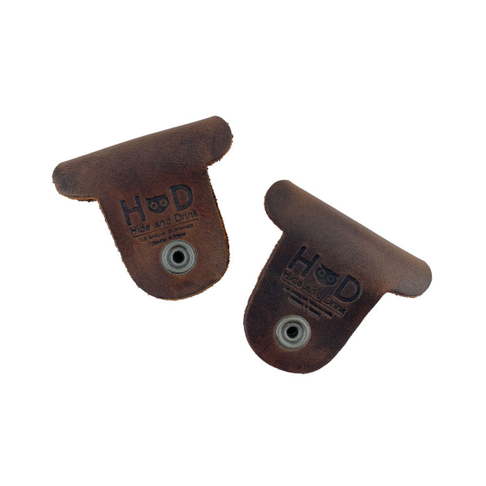 Two dark brown Dog Shaped Cord Keepers showing the Hide & Drink branding, crafted from premium Full Grain Leather for effective cord organization. Dog Shaped Cord Keeper (Cord Clam) 2-Pack, Full Grain Leather, StockyardX, Small Batch Production, Hand Cut, Hand Sewn, Fire Branded, Artisan, Handmade in La Antigua Guatemala & Oaxaca Mexico.