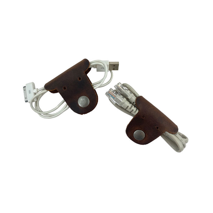 Two dark brown Dog Shaped Cord Keepers managing USB cables, an innovative way to keep cords tidy and organized by Hide & Drink, made from Full Grain Leather. Dog Shaped Cord Keeper (Cord Clam) 2-Pack, Full Grain Leather, StockyardX, Small Batch Production, Hand Cut, Hand Sewn, Fire Branded, Artisan, Handmade in La Antigua Guatemala & Oaxaca Mexico.