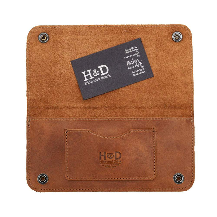 Detailed view of the Brown Double Snap Folio Wallet by Hide & Drink, showcasing its high-quality full grain leather texture. This accessory serves as a rectangular flat bill holder with card slot, ideal for a night bag or travel accessory. Artisanally crafted in La Antigua Guatemala & Oaxaca Mexico, representing the charm of small batch production.