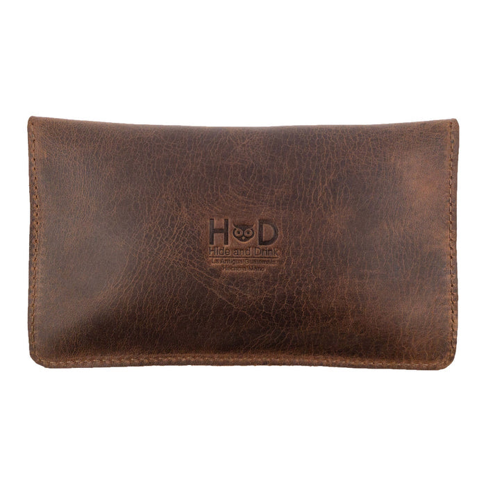 Back view of the Double Snap Tobacco Pouch by Hide & Drink, highlighting the elegant texture of full grain leather. This smoking case combines functionality with classic style, perfect for all your travel accessory needs. Hand cut and hand sewn, its fire branded logo reflects quality craftsmanship from Oaxaca Mexico.