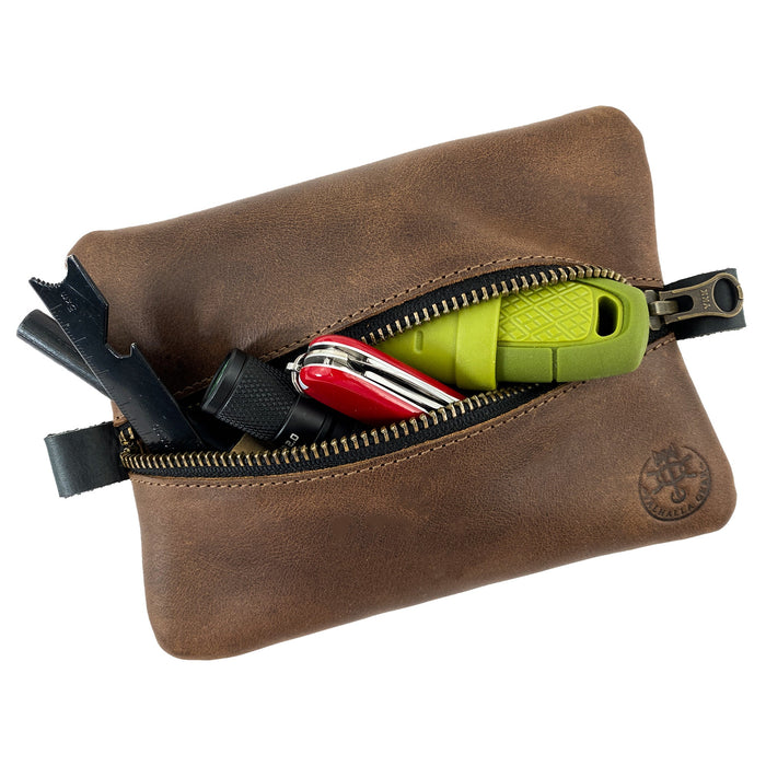 The EDC Zippered Pouch by Valhalla Gear filled with essential tools, demonstrating its practicality. This handmade accessory bag from full grain leather is perfect for organizing small personal items, showcasing exceptional artisan craftsmanship and small batch production from La Antigua Guatemala.