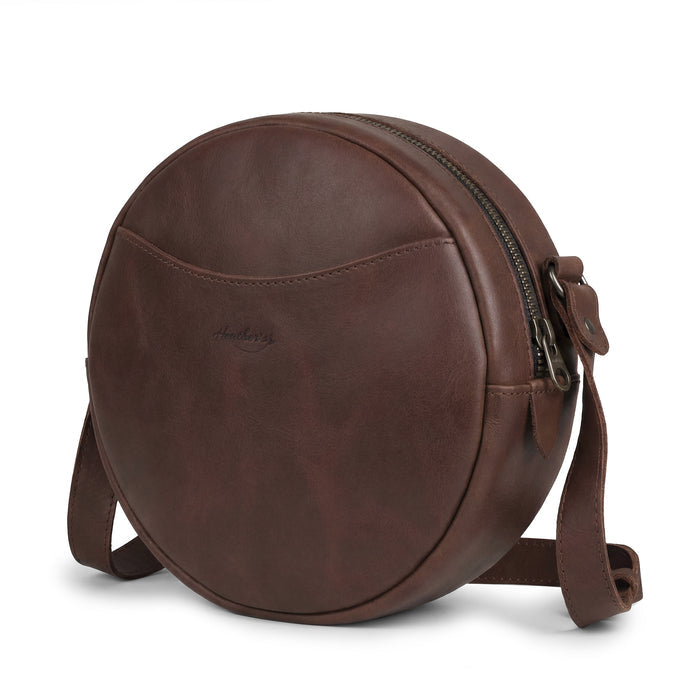 Heather's Female Rounded Crossbody Hand Bag made of Full Grain Leather, featuring a stylish design perfect for any occasion. This Rounded Crossbody bag for women is a zippered handbag that combines fashion and functionality. Handmade in La Antigua Guatemala, it showcases small batch production with hand cut and hand sewn details, proudly fire branded by artisans.