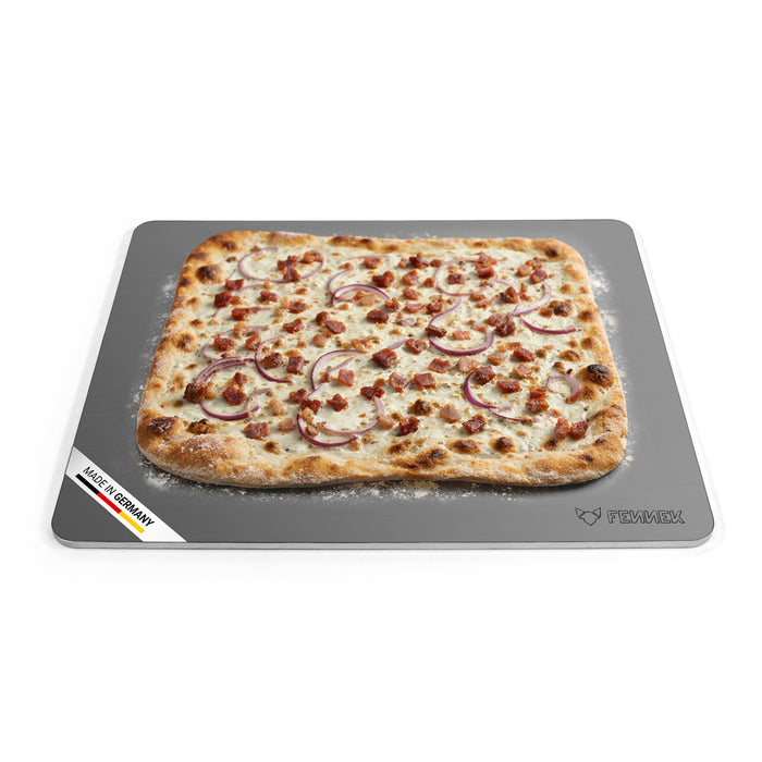 Titelbild vom FENNEK Backstahl mit den Abmessungen 46 x 38 (L x B). Zu sehen ist ein klassischer Flammkuchen, der auf dem Backstahl gebacken wurde. Unten links an der Ecke des Backstahls verdeutlicht eine Banderole, dass der FENNEK Backstahl Made in Germany ist.