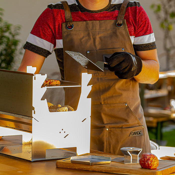 BBQ-Wender im Einsatz wird gehalten von einer Person mit Grillschürze und Grillhandschuh.