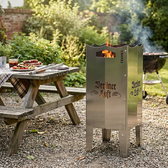 Freisteller der FENNEK Berliner Luft Feuersäule mit dem ausgelasertem Schriftzug "Berliner Luft" in altdeutscher Schrift. Im Inneren der Feuersäule brennt ein Feuer, dessen Flammen durch den Schriftzug herausleuchten. Die Tonne steht im Freien.