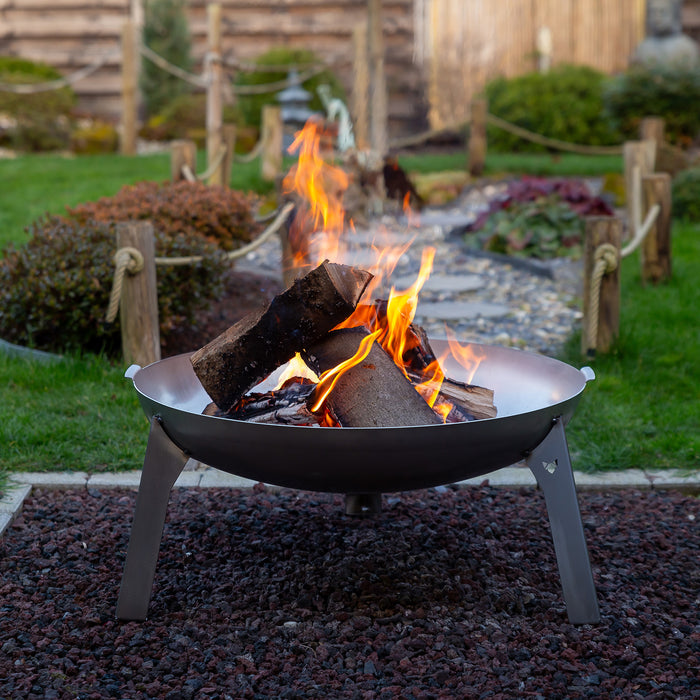 Ein schönes Lagerfeuer in der Feuerschale Edelstahl, welche auf einem Kiesbett steht in einem schön angelegten Garten..