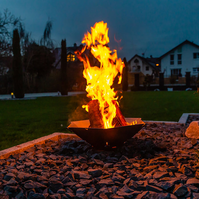 Brennendes Feuer in der Feuerschale Hexagon bei Dunkelheit im Garten..