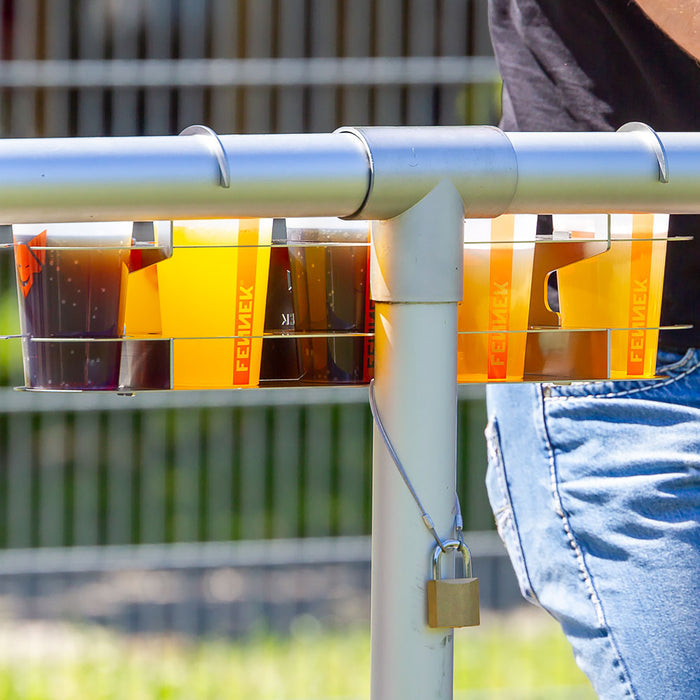Getränkehalter aus Edelstahl für 5 Getränke, montiert am Sportplatz und befüllt mit Bechern mit Cola und Fanta. Man kann die Diebstahlsicherung sehen.