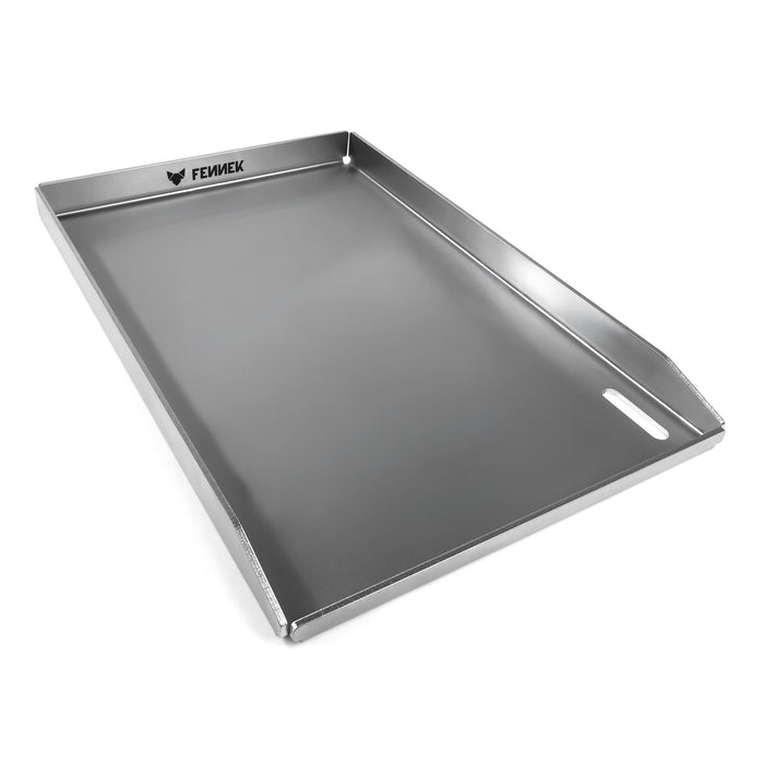 Freisteller der FENNEK Plancha 45 x 30 x 3,5 cm. Sie hat eine hochgezogene Vorderkante, damit kein Grillgut herunterfallen kann. Zusätzlich hat sie vorne rechts in der Ecke ein großzügiges Ablaufloch, worüber überschüssiges Fett und Grillreste in die Fettauffangwanne entsorgt werden können. Die vier Ecken sind offen, damit hier auch das überschüssige Fett abgeleitet werden kann. Ein Hingucker ist der eingravierte FENNEK Schriftzug.