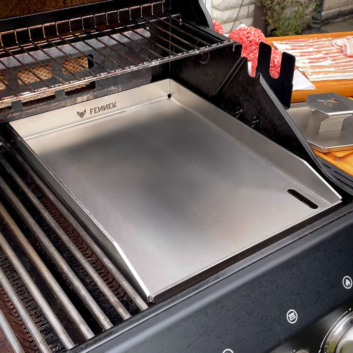 Die FENNEK Plancha 30 x 40 als Rostersatz in einem Gasgrill. Rechts auf der Ablage daneben ist der FENNEK Smasher zu sehen.