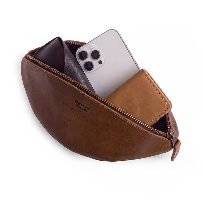 Inside view of the Football Toiletry Bag by Hide & Drink, featuring grooming tools neatly organized. This travel organizer is ideal for storing shaving kits and other essentials. Made from full grain leather, the Gameday Football Dopp Toiletry Bag reflects artisan craftsmanship from La Antigua Guatemala and Oaxaca Mexico, showcasing hand cut, hand sewn, and fire branded details.