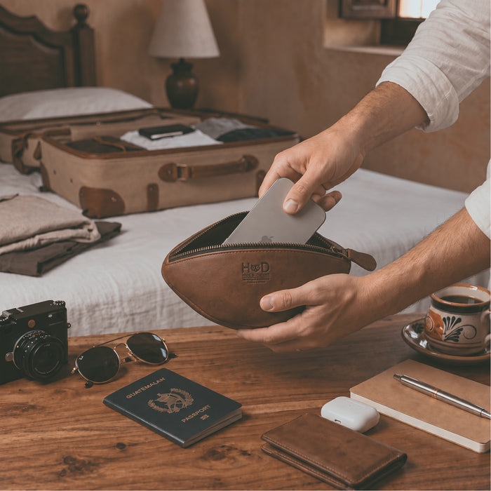 Top view of the handmade Football Toiletry Bag by Hide & Drink, showcasing its rustic design featuring full grain leather and suede details. This Gameday Football Dopp Toiletry Bag serves as a stylish travel organizer and a durable bag for grooming essentials, perfect for shaving kit storage. Crafted with care in La Antigua Guatemala, this artisan-made piece exemplifies small batch production with hand-cut and hand-sewn techniques.