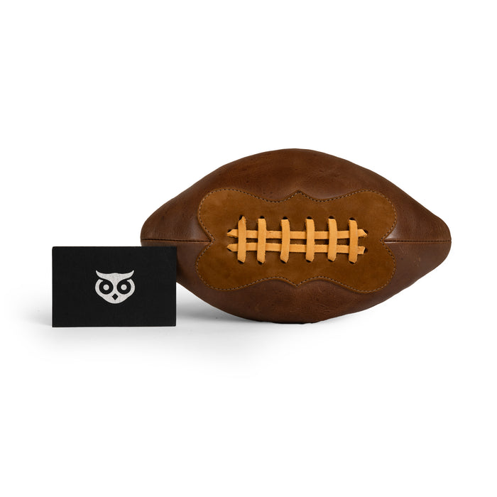 Football Toiletry Bag by Hide & Drink showcased with tags, highlighting its unique design and artisan quality. This Gameday Football Dopp Toiletry Bag is perfect for travel organization and grooming essentials, made from durable full grain leather. Featuring hand cut, hand sewn, and fire branded details, this handmade piece exemplifies craftsmanship from La Antigua Guatemala and Oaxaca Mexico.