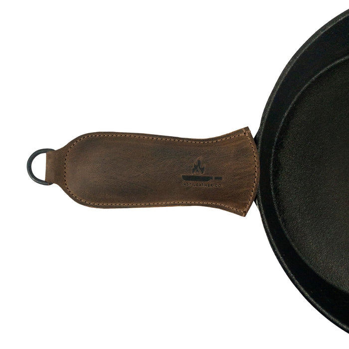 Hanging Pan Handle Cover by Cast Leather Co., featuring a comfortable Hot Handle Panhandle with Half Ring that offers a secure grip. This full grain leather accessory ensures your cookware slides on/off easily onto metal skillet grips, embodying the artisan craftsmanship of small batch production from La Antigua Guatemala & Oaxaca Mexico.