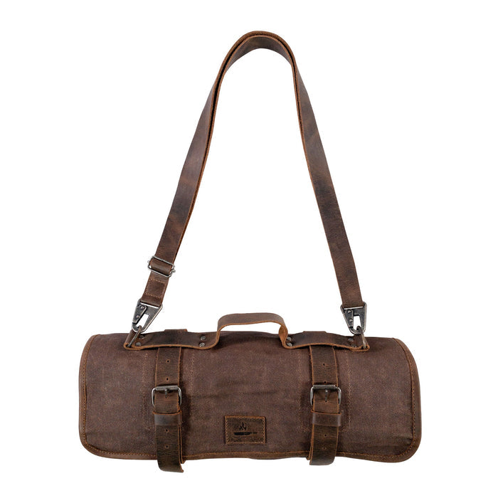 The Knife Roll with 8 Slots by Cast Leather Co. is displayed slung over the shoulder in a stylish way. This rugged travel bag combines functionality and artisanal craftsmanship, ideal for chefs and cooking enthusiasts. Made of waxed canvas and full grain leather, it showcases the essence of handmade items from La Antigua Guatemala.