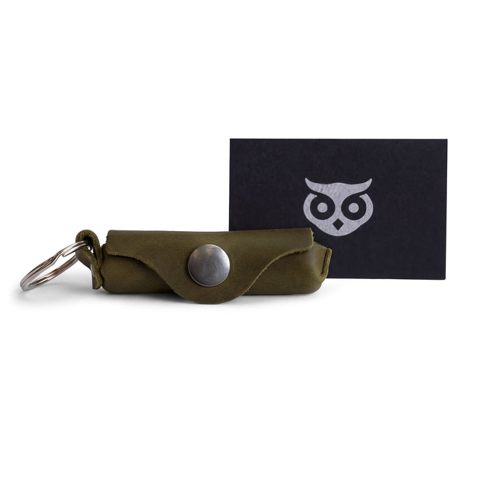 A collection of accessories including the Hide & Drink Lip Balm Key Chain displaying its artisan quality and design. This classic vintage lip balm keychain holder is perfect for securing your lip balm while providing excellent protection. Crafted from full grain leather with a brass metal clasp, it highlights the artistry of small batch production, handmade in La Antigua Guatemala & Oaxaca Mexico.