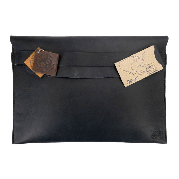 The back of the Hide & Drink MacBook Slim Case featuring a decorative leather tag, emphasizing its artisan touch. Ideal for MacBook Air/Pro 13 Inch with M1 Chip, this case is crafted from full grain leather with small batch production, showcasing unique handmade craftsmanship.