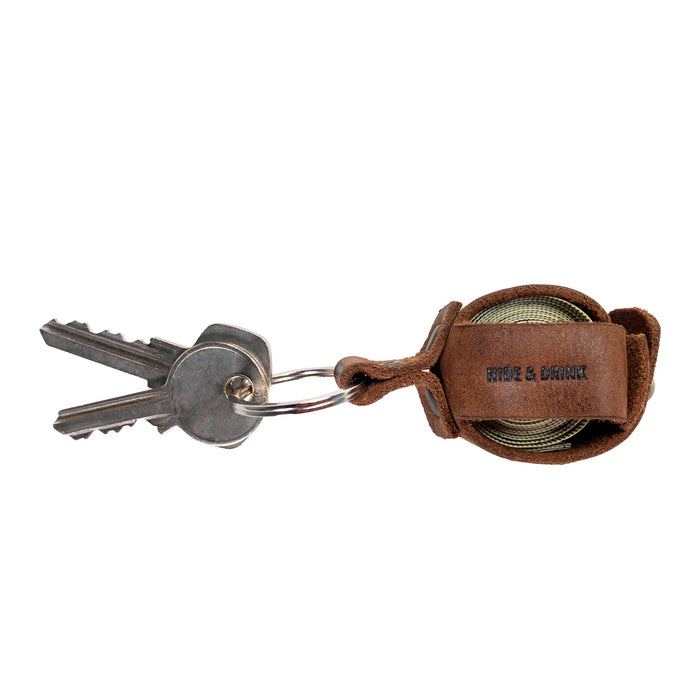 Hide & Drink Measuring Tape Holder Keychain with keys attached, designed to securely hold measuring tape (Tape not Included). Made from premium Full Grain Leather, this key ring organizer is a stylish addition for tailor accessories. Crafted through small batch production, showcasing hand cut, hand sewn materials with fire branded details, all handmade in La Antigua Guatemala & Oaxaca Mexico.