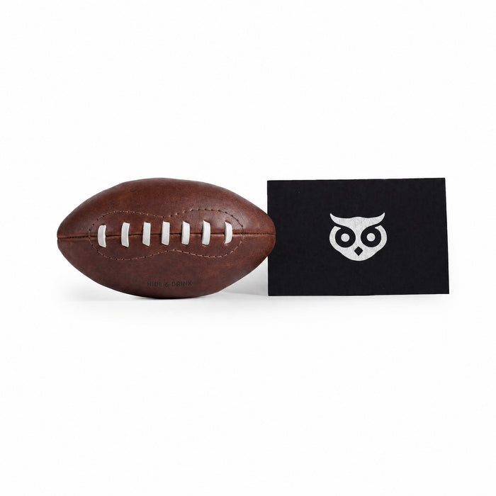 Mini American Football by Hide & Drink along with care cards showcasing its artisan heritage. This hand stitched ball is made from full grain leather, perfect as a keepsake or decorative piece, highlighting the unique craftsmanship from La Antigua Guatemala & Oaxaca Mexico.