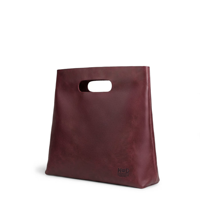 The side profile of the red Minimalist Boho Handbag by Hide & Drink, showcasing its unique design and structure. This Minimalist Handbag for Women functions as a chic Tote Bag, made from beautiful Full Grain Leather, reflecting StockyardX‚Äôs artisan dedication to Small Batch Production, with each piece Handmade in La Antigua Guatemala & Oaxaca Mexico.