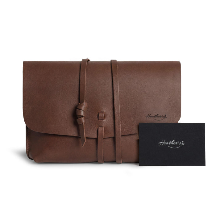 Heather's Minimalist Clutch Bag featuring a tag that highlights its artisan quality. This full grain leather bag is perfect for cards, money, and coins, and also makes a great storage solution for cosmetics and toiletry items. Handmade through small batch production in La Antigua Guatemala & Oaxaca Mexico.