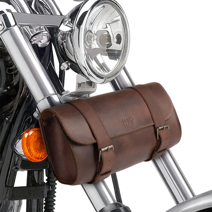 Hide & Drink Leather Motorcycle Tool Bag strapped on a motorcycle, made of high-quality Full Grain Leather, ideal for those in need of a robust Biker Bag for Tools and Essentials. Designed as a Handlebar Bag with Adjustable Straps, it serves as a practical Tool Organizer, Hand Cut, Hand Sewn, and crafted in La Antigua Guatemala & Oaxaca Mexico.