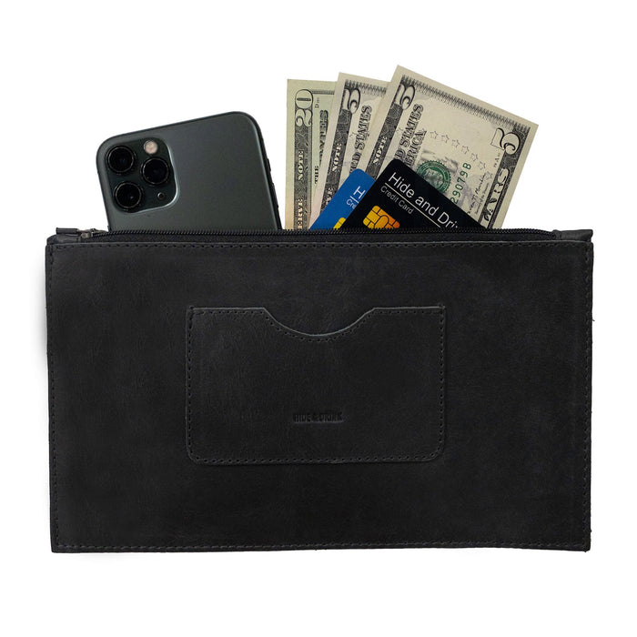 A sleek black rectangular zippered handbag by Hide & Drink, designed for women, featuring a card slot filled with cash and a smartphone. This female purse is made from full grain leather and reflects artisan crafting techniques showcasing small batch production, hand cut and sewn in La Antigua Guatemala & Oaxaca Mexico.