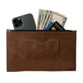 A brown rectangular zippered handbag by Hide & Drink featuring cash and a smartphone inside, designed for women. This full grain leather purse comes with a card slot, reflecting artisan craftsmanship and small batch production, hand cut and sewn in La Antigua Guatemala & Oaxaca Mexico.
