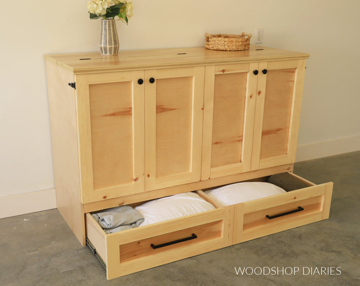 DIY murphy bed cabinet with bottom drawers open showing pillow and bedding storage