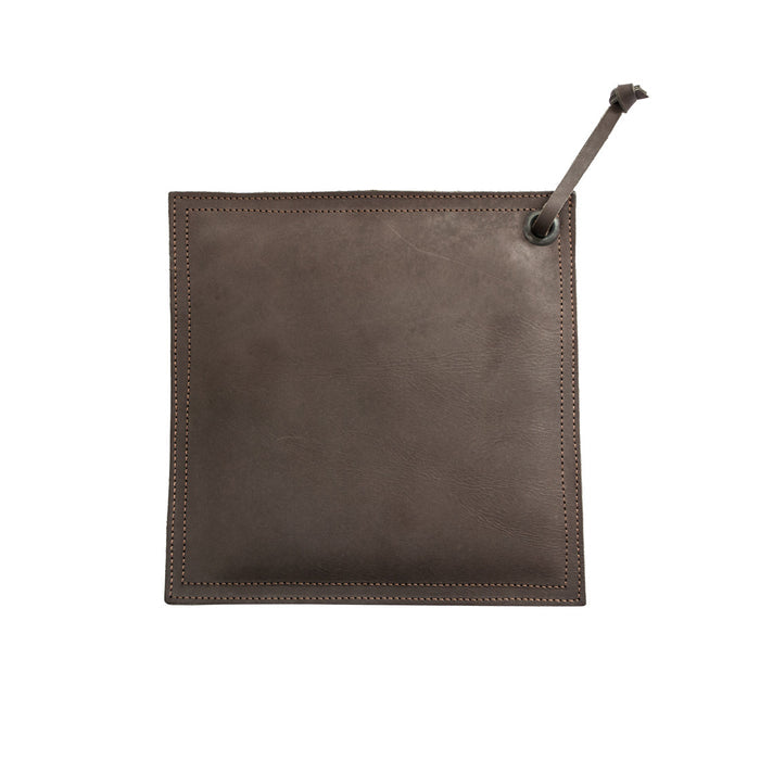 Hide & Drink Pot Pad displayed next to a cast iron skillet, emphasizing its craftsmanship and functionality as a rustic hot pot pad.
