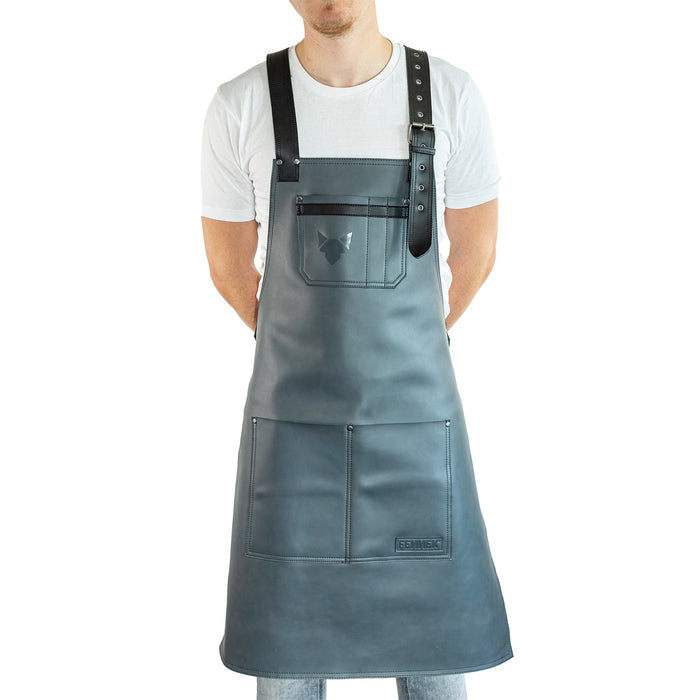Brustbereich Leder-Grillschürze mit geprägtem FENNEK-Logo und mit verstellbarem Lederriemen, Schnalle und aufgesetzten Taschen, getragen von einem Mann