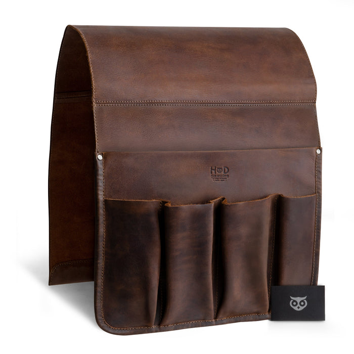 Hide & Drink Remote Control Holder showcasing its rich, dark leather and stylish pockets for remotes and magazines. This artistic piece exemplifies handmade craftsmanship from La Antigua Guatemala, emphasizing its role as a sophisticated sofa armrest organizer pouch.