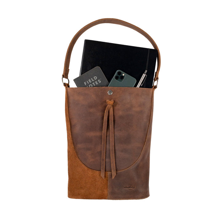 The interior of Heather's Reversed Shoulder Bag filled with essentials, emphasizing its spacious design. This rustic tote bag for women exemplifies a vintage purse style with a shoulder bag strap, made of full grain leather and created through artisan craftsmanship in La Antigua Guatemala & Oaxaca Mexico.