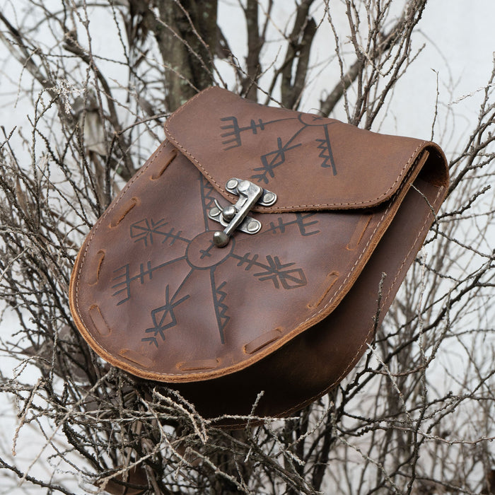 Rune Belt Pouch from Hide & Play, showcasing a beautiful medieval style waist bag perched on a branch. Handcrafted from full grain leather, this Viking waist bag is ideal for costume parties and LARPing, made with care in La Antigua Guatemala through artisan methods including fire branding.