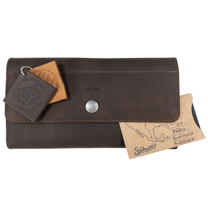 The Rustic Tri Fold Folio Wallet by Hide & Drink displayed with tags, emphasizing its unique character and artisan quality. This wallet is the ideal Minimalist Tri Fold Folio Wallet for Women, made from full grain leather with an emphasis on small batch production, showcasing hand cut and hand sewn craftsmanship, proudly handmade in La Antigua Guatemala & Oaxaca Mexico.