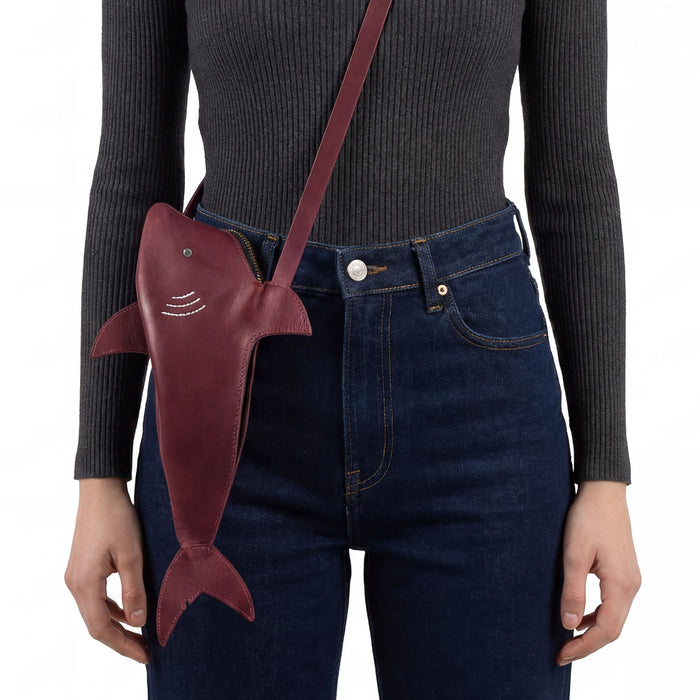 A person modeling the Shark-Shaped Shoulder Bag by Tudi Frudi, showcasing the adjustable strap. This unique bag combines style and practicality, perfect for crossbody or messenger wear. Crafted with Full Grain Leather, it represents artisan, handmade quality from La Antigua Guatemala.