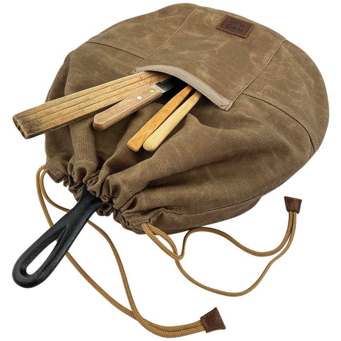Skillet Bag Cover by Hide & Drink, featuring utensils stored in the front pocket. This handmade bag is perfect for a case for skillet without nonstick coating, crafted from enduring waxed canvas and showcasing expert craftsmanship from La Antigua Guatemala and Oaxaca Mexico.