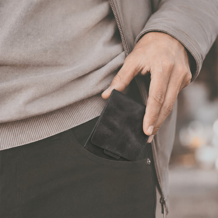 Hide & Drink Slim Card Holder in black leather, an elegant wallet designed to hold up to 4 cards and folded bills. This pocket wallet embodies handmade craftsmanship from artisans in La Antigua Guatemala, featuring fire branded artisan details.