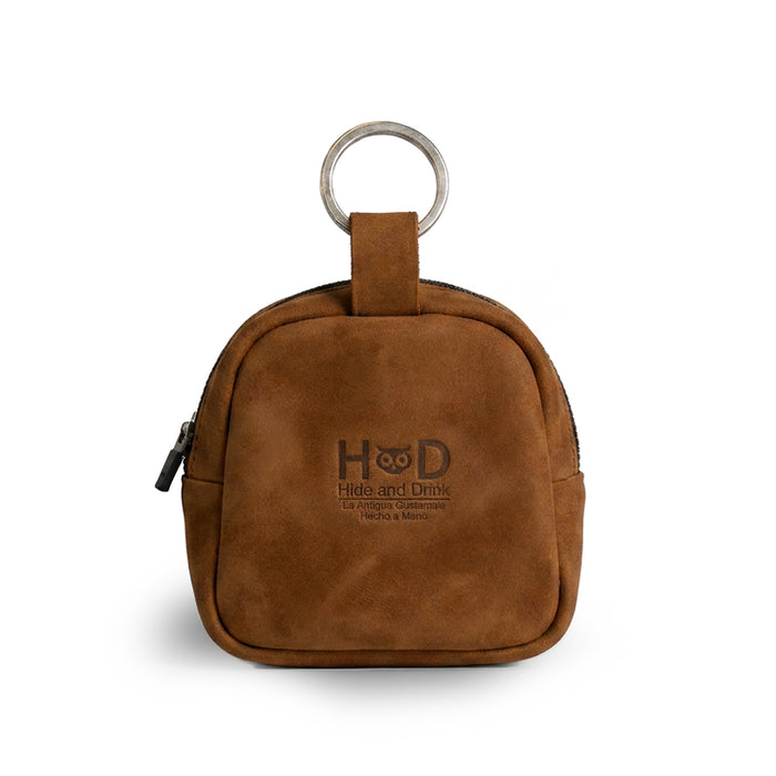 Showcasing the back view, The Pouty Pup Mini Pack by Hide & Drink features a sleek design in soft brown suede leather, making it a stylish choice for a mini backpack or wallet. This mini pouch is perfect for organizing cables or small items, crafted with care by artisans in La Antigua Guatemala & Oaxaca Mexico.