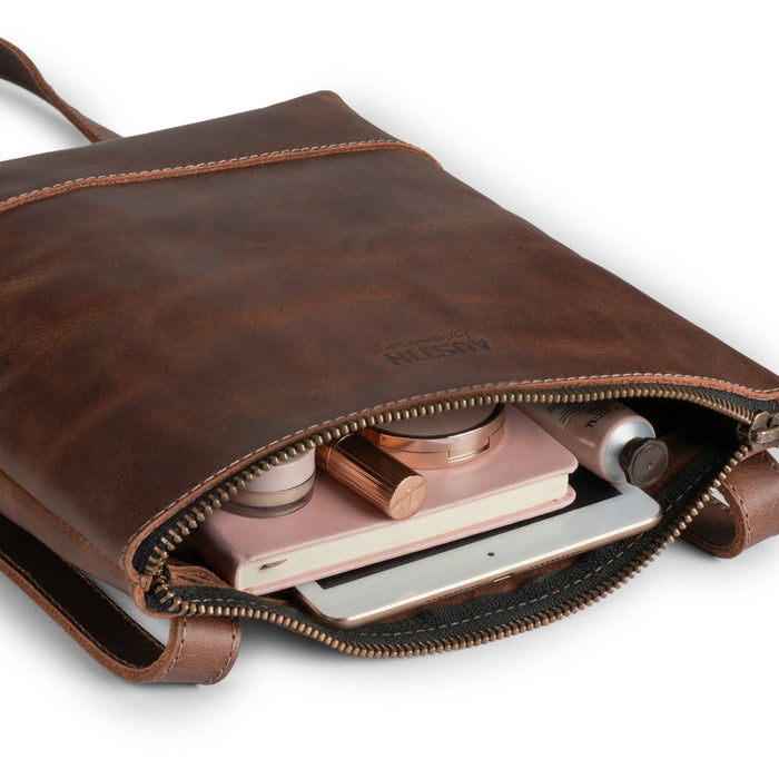 The Zilker Crossbody Bag by Austin Genuine, unzipped to reveal its spacious interior, crafted from full grain leather and designed with the vibrant culture of Austin in mind, showcasing artisan craftsmanship and small batch production.