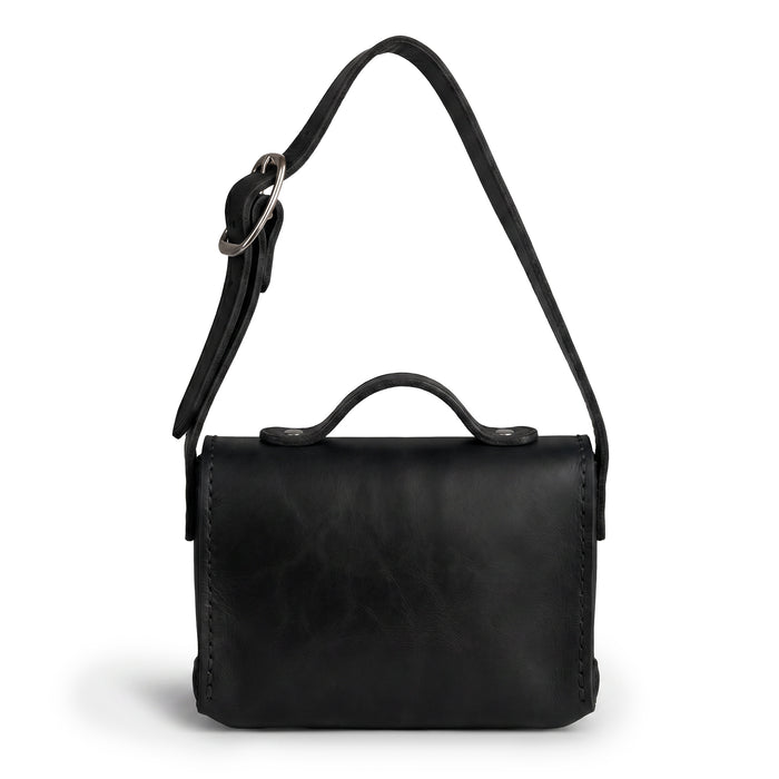 Back view of the Black Tiny Messenger Bag by Hide & Drink, showcasing its sleek design made from premium Full Grain Leather. This Mini Messenger Bag Charm is a perfect keychain or handbag attachment, representing artisan craftsmanship and small batch production in La Antigua Guatemala.